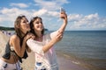 Two happy girls taking selfie on beach having fun