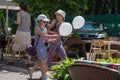 Two happy girls walking on street with baloons during children protection day