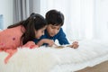 Two happy Indian brother and sister in traditional clothing lying on bed and reading book, having fun together at home. Education Royalty Free Stock Photo