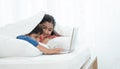 Two happy Indian brother and sister in traditional clothing lying on bed under blanket smiling, using laptop, having fun together Royalty Free Stock Photo