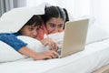 Two happy Indian brother and sister in traditional clothing lying on bed under blanket smiling, using laptop, having fun together Royalty Free Stock Photo