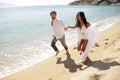 Two happy just married young adults, men holding his wife, running in the water, isolated on a seascape background. Royalty Free Stock Photo
