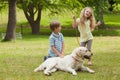 Two happy kids with pet dog at park