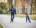 Two happy kids ride in autumn park on rollerblades Royalty Free Stock Photo
