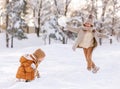 Two happy kids throwing snowballs at each other while playing with snow in winter park Royalty Free Stock Photo