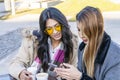 Two happy latin women friends sharing a smart phone in a coffee shop terrace looking at device in winter Royalty Free Stock Photo