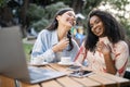 Two Happy Laughing Young Women Using Laptop In Cafe Outdoors