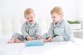 Two happy little boys brothers twins in pajamas reading book in their parents bed