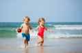 Boy and sister girl run on the sand beach smiling over sea waves Royalty Free Stock Photo