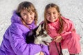 Two Happy little girls holding puppy dog husky on the snow Royalty Free Stock Photo