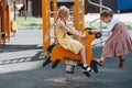 Two happy little girls playing with a spring horse on a children playground