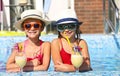 Two happy little girls in sunglasses with cocktails wearing hats