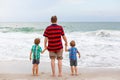 Two happy little kids boys and father standing on the beach of ocean and looking on horizon on stormy day. Family, dad Royalty Free Stock Photo