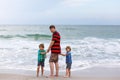 Two happy little kids boys and father standing on the beach of ocean and looking on horizon on stormy day. Family, dad Royalty Free Stock Photo