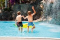 Two happy little kids boys jumping in the pool and having fun on family vacations in a hotel resort. Healthy children Royalty Free Stock Photo