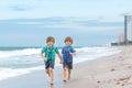 Two happy little kids boys running on the beach of ocean. Funny cute children, sibling and best friends making vacations Royalty Free Stock Photo