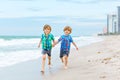 Two happy little kids boys running on the beach of ocean. Funny cute children, sibling and best friends making vacations Royalty Free Stock Photo