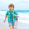 Two happy little kids boys running on the beach of ocean. Funny cute children, sibling and best friends making vacations Royalty Free Stock Photo
