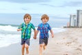 Two happy little kids boys running on the beach of ocean. Funny cute children, sibling and best friends making vacations Royalty Free Stock Photo