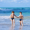 Two happy little kids boys running on the beach of ocean. Funny cute children, siblings, twins and best friends making Royalty Free Stock Photo