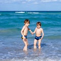 Two happy little kids boys running on the beach of ocean. Funny cute children, siblings, twins and best friends making Royalty Free Stock Photo