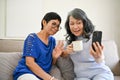 Two happy middle-aged Asian women talking with their grandchild through a video call Royalty Free Stock Photo