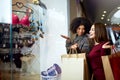 Two happy multiethnic young mixed race woman shopping for lingerie near clothing boutique shop window, decide whether to