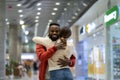 Two happy multiracial friends hugging at airport, loving multiethnic couple embracing in terminal Royalty Free Stock Photo