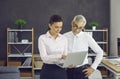 Two business people standing in office and looking at something on laptop screen Royalty Free Stock Photo