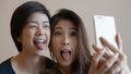 Two happy photogenic Asian womans talking selfie with phone