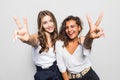 Two happy pretty women posing together and showing peace gestures while looking at the camera over gray background Royalty Free Stock Photo