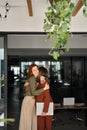 Two happy business women standing at work in office hugging, vertical. Royalty Free Stock Photo