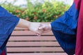 Two happy proud PhD graduated male students in Academic dress gown shake hands and congratulate each other