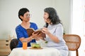 Two happy retired Asian female close friends are discussing something in a book Royalty Free Stock Photo
