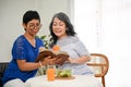 Two happy retired female are discussing something in a book while enjoying their healthy brunch Royalty Free Stock Photo