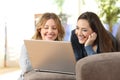 Two roommates watching on line content in a laptop at home