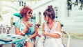 Two happy senior women in a sunglasses talking and drinking coffee in a outdoor cafe Royalty Free Stock Photo