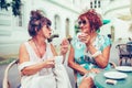 Two happy senior women talking and drinking coffee while looking each other Royalty Free Stock Photo