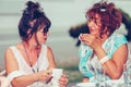 Two happy senior women talking and drinking coffee  in a outdoor cafe Royalty Free Stock Photo