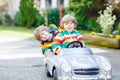 Two happy sibling boys playing with big old toy car Royalty Free Stock Photo