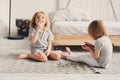 Two happy sibling boys playing together at home with toy cars