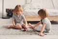 Two happy sibling boys playing together at home with toy cars