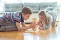 Two happy siblings playing a game with wooden blocks at home