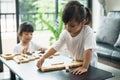 Two happy siblings playing a game with wooden blocks at home joyfully Royalty Free Stock Photo