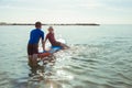 Two happy siblings teen children in neoprene suits having fun with sup board in Baltic sea