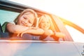 Two happy sisters looking out open car window during auto trip. Cute girls are smiling, laughing during road jorney. Family values