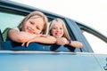 Two happy sisters looking out open car window during auto trip. Cute girls are smiling, laughing during road jorney. Family values