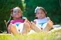 Two happy sisters lying on green grass