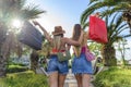 Two happy sisters with shopping bags walking outdoor on palm trees route in day time. beautiful women having fun on summer shop Royalty Free Stock Photo