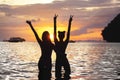 Two happy slim girls raised arms sunset sea Royalty Free Stock Photo